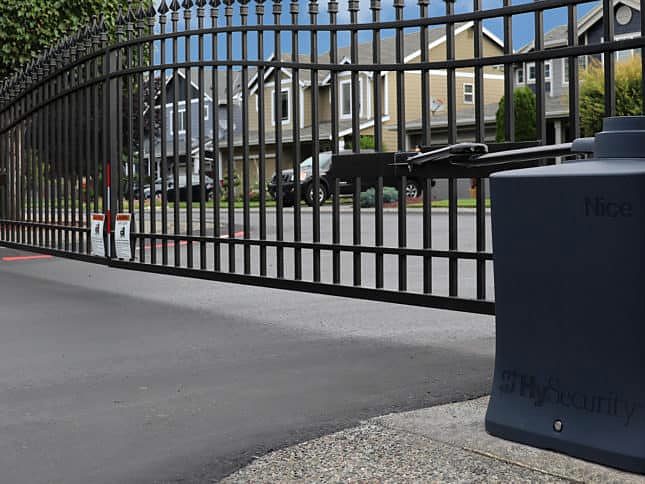 Black metal swing gate and gate operator at a residential entrance
