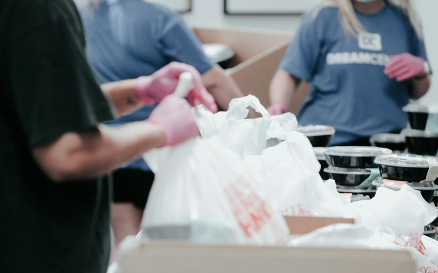 Volunteers in gloves packing food into bags at a food bank