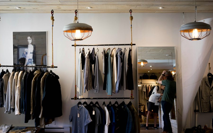 Clothing boutique with garments on hanging racks and pendant lights