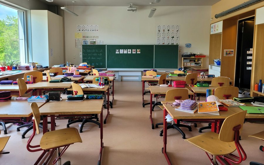 Empty elementary school classroom with desks, chairs, and a chalkboard
