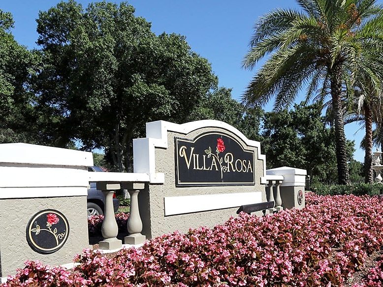 Villa Rosa community entrance sign with red flowers and palm trees